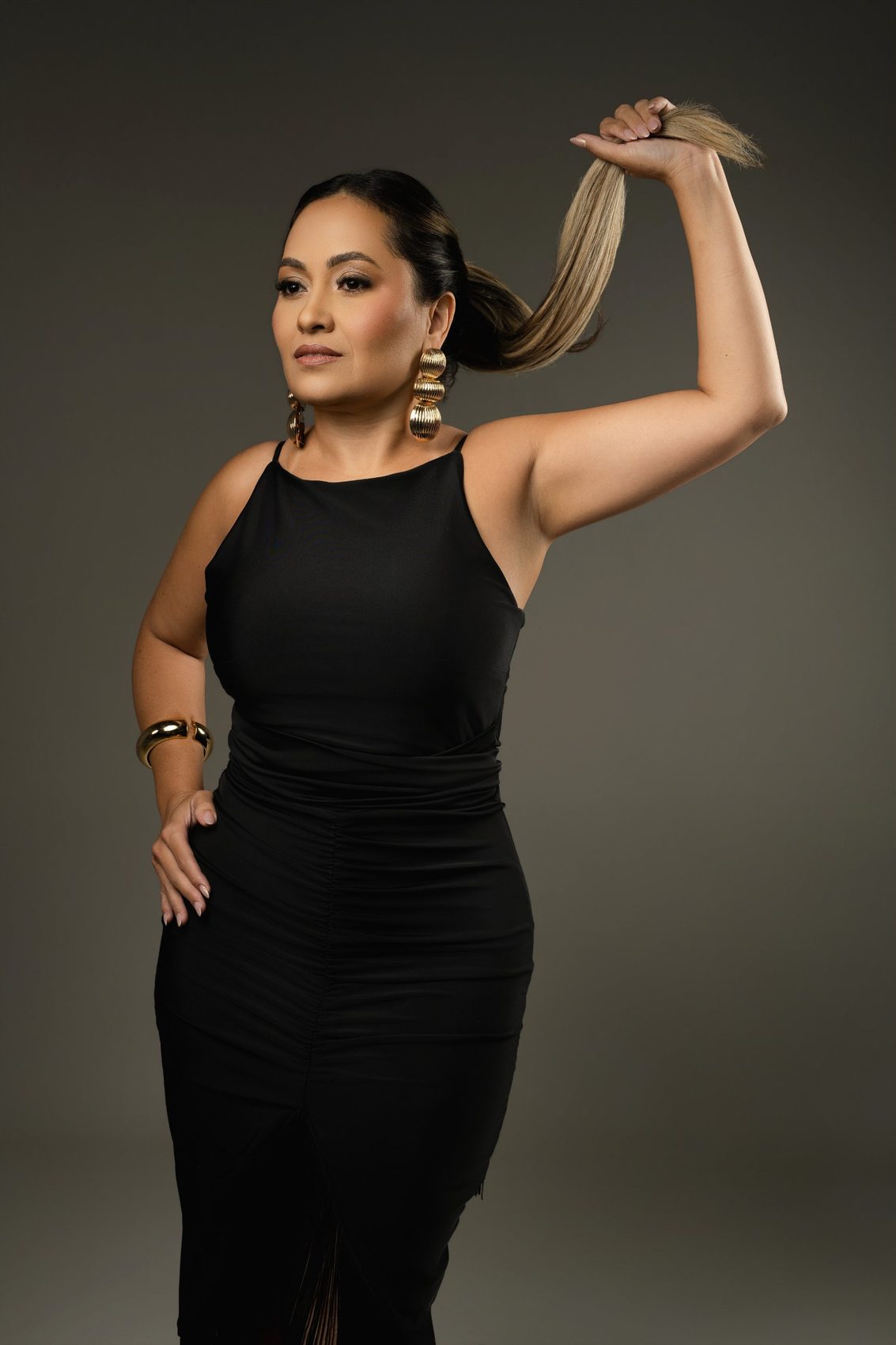 Meirielle Ribeiro de vestido preto, segurando o cabelo